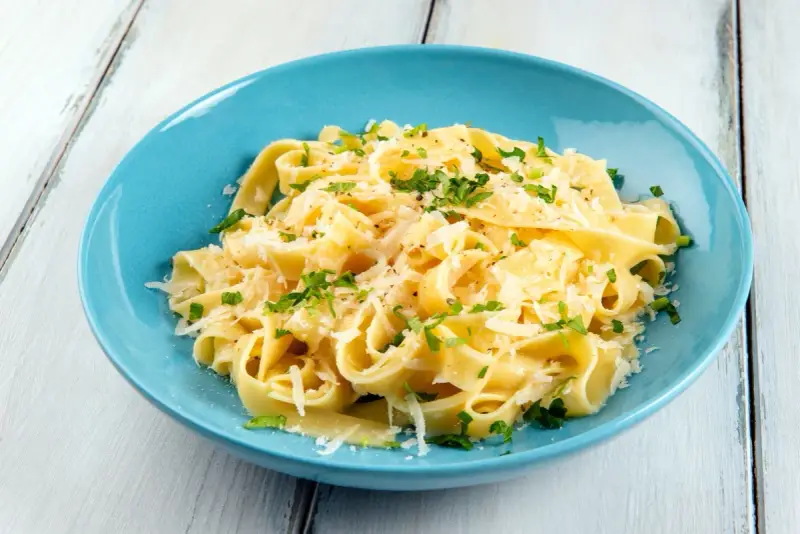 Fettuccine al burro e parmigiano, uno dei sughi per pasta più semplici e gustosi, guarnito con prezzemolo fresco.