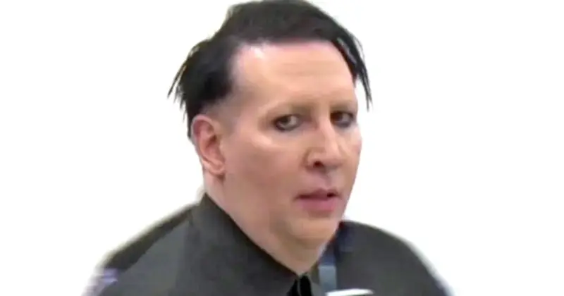 Marilyn Manson bez makijażu, z charakterystycznym makijażem oczu, w czarnej koszuli.