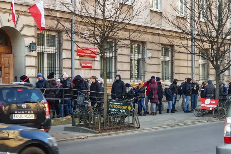 Kolejka do odbioru paszportu w Krakowie. Ludzie stoją przed budynkiem urzędu.