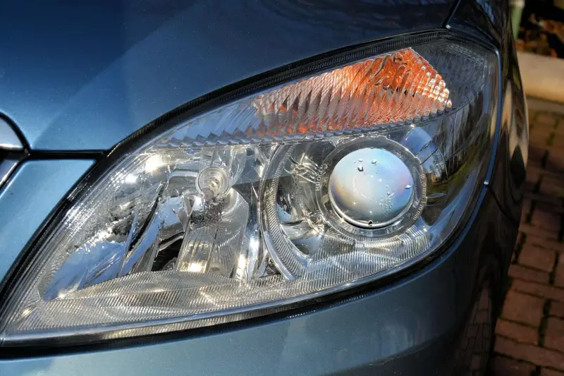 Zbliżenie na reflektor samochodu, gdzie widać soczewkę z kroplami wody. W tym miejscu znajdują się odpowietrzniki w reflektorach, zapobiegające parowaniu.