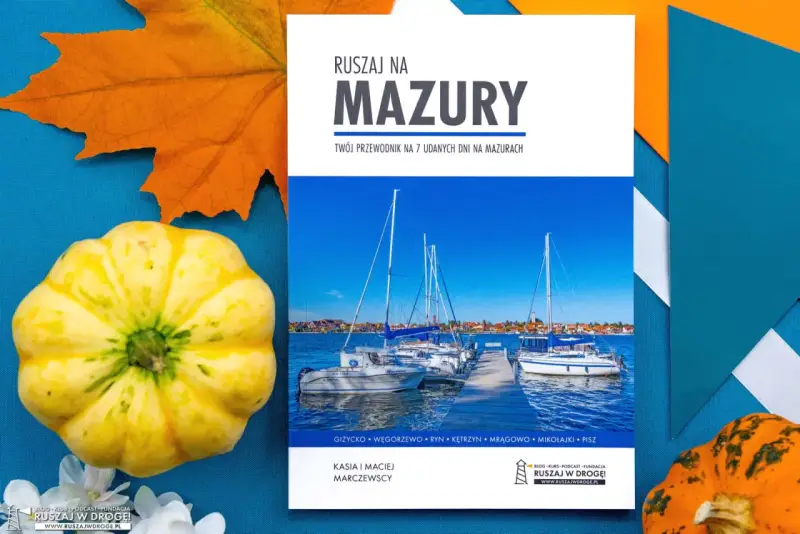 Przewodnik "Ruszaj na Mazury" z widokiem na żaglówki i miasteczko. Idealny na podróż po krainie tysiąca jezior.