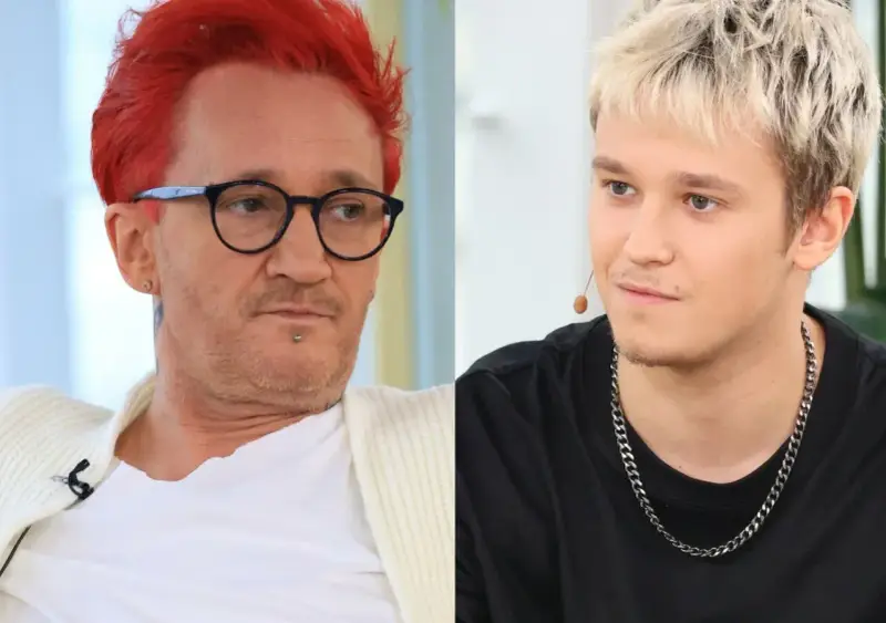 Xavier Michał Wiśniewski z charakterystycznymi rudymi włosami i okularami obok młodszego mężczyzny z blond fryzurą.