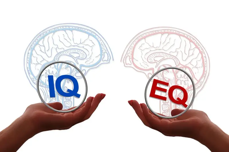 Dwie dłonie trzymają symbole IQ i EQ, symbolizujące równowagę między inteligencją a inteligencją emocjonalną.