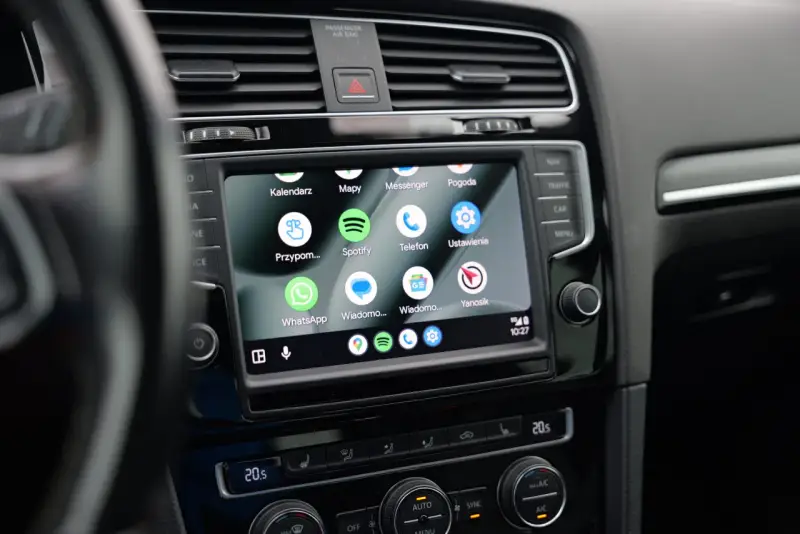 Ekran samochodu z widoczną aplikacją Android Auto, wyświetlającą ikony Kalendarz, Mapy, Spotify, WhatsApp i inne.