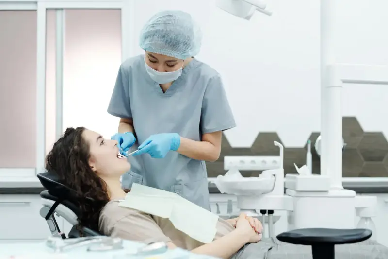 Dentystka bada zęby pacjentki, szukając oznak problemów, które mogą wymagać leczenia kieszonek dziąsłowych.
