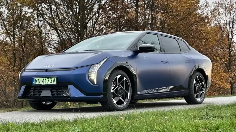 Niebieski Polestar 2 na tle jesiennych drzew. Elegancki samochód elektryczny z charakterystycznymi światłami i felgami.