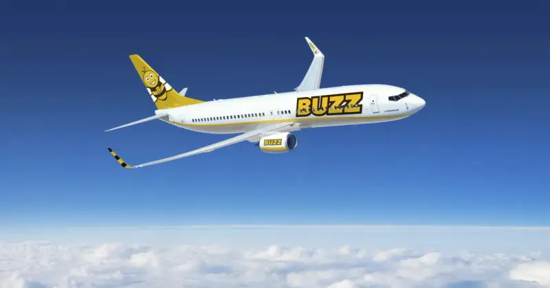 Samolot Buzz, należący do Ryanair, leci nad chmurami. Idealny na wakacje, zabierze Twój bagaż w słoneczne miejsce.