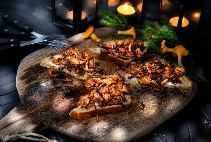 Smörstekta kantareller på bröd, ett enkelt och gott kantareller recept. Serveras på en träbricka med ljus och granris.