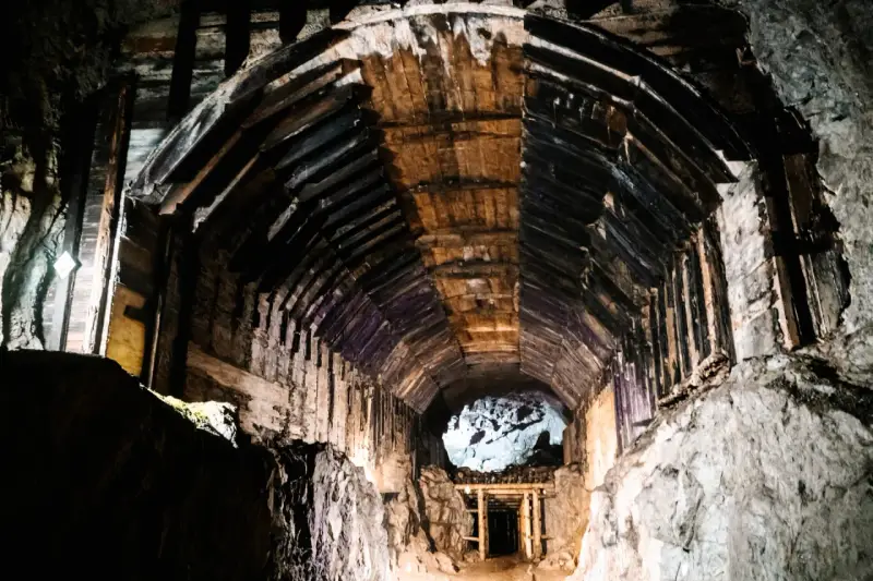 Wnętrze kopalni, drewniane wsporniki tworzą tunel, który prowadzi do jasnego otworu. To część kompleksu Rize.