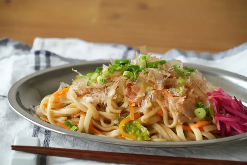Udon z warzywami i szczypiorkiem, posypany płatkami katsuobushi. To właśnie katsuobushi co to jest, suszone płatki bonito, dodają daniu głębi smaku.