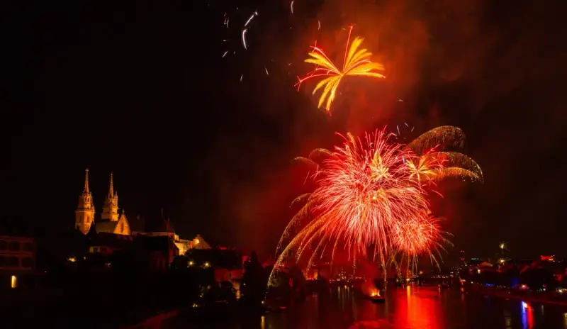 Feu d'artifice rougeoyant illuminant le ciel nocturne au-dessus d'une ville et d'une rivière. Le **décibel feu d'artifice** résonne dans l'air.