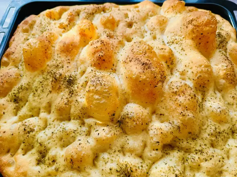 Chrupiąca pizza focaccia z ziołami, świeżo wyjęta z pieca. Idealna na przekąskę.