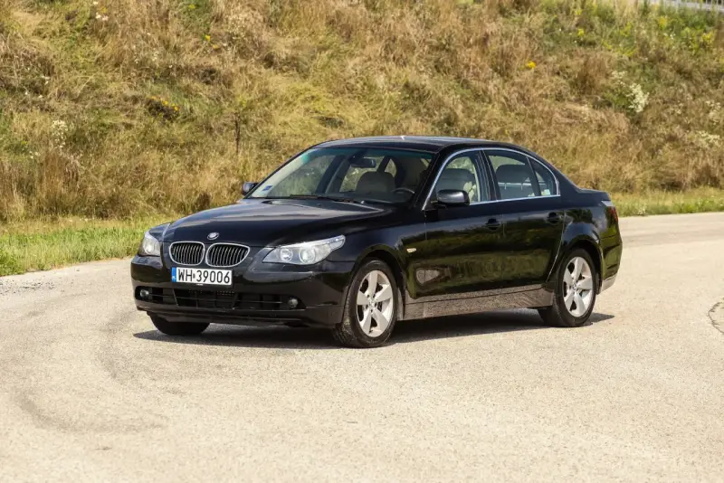 Czarne BMW 535d na tle zielonego wzgórza.