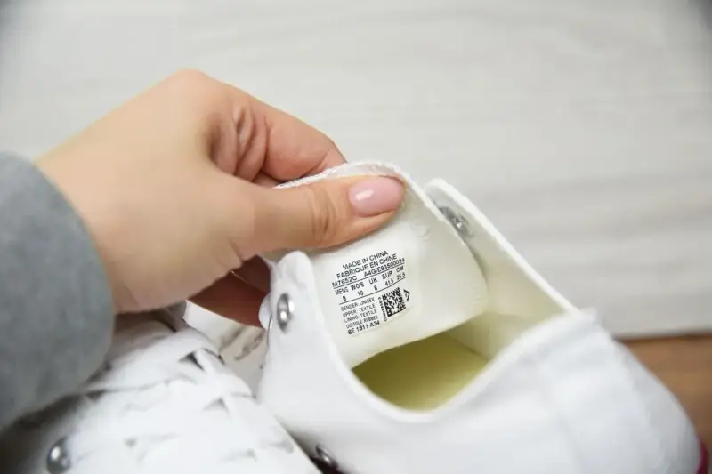 Porównanie converse oryginalne a podróbki. Dłoń pokazuje metkę z rozmiarem na białym bucie.