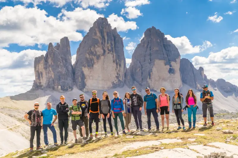 Grupa przyjaciół na tle Tre Cime di Lavaredo podczas niezapomnianego trekkingu w Dolomitach.