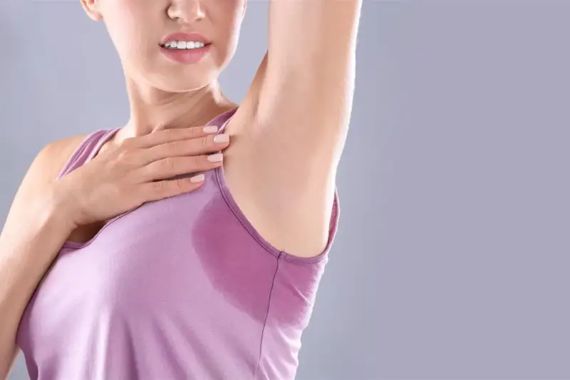 Donna con ascella bagnata, un segno di sudorazione eccessiva. Le cause possono essere molteplici, dallo stress al caldo.