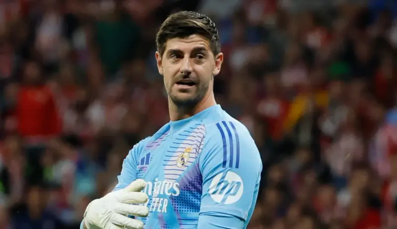 Bramkarz Realu Madryt, Thibaut Courtois, w jasnoniebieskiej koszulce z rękawicami, gotowy do obrony.