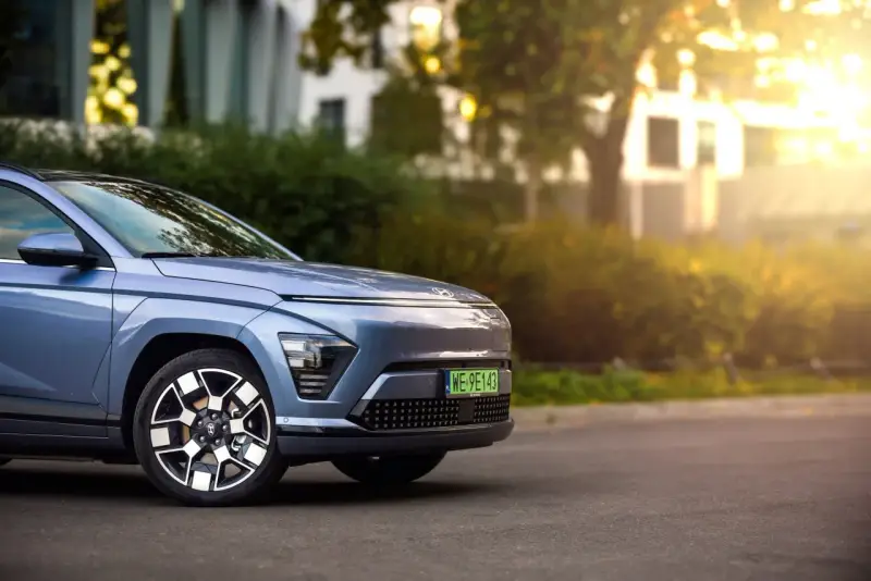 Niebieski Hyundai Kona Electric zaparkowany na ulicy, z widocznym przodem i kołem.
