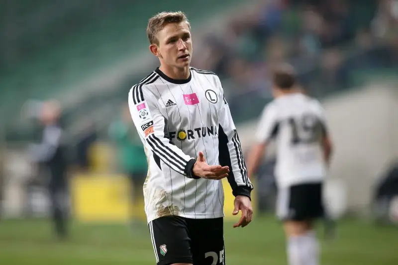 Kuba Rzeźniczak w białej koszulce z czarnymi pasami, na boisku.