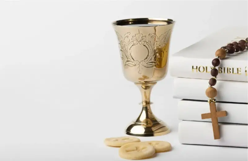 Złoty kielich, hostie, różaniec i Biblia. Symbolika sakramentu, który może być odnotowany w akcie chrztu.