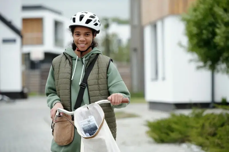 Junges Mädchen mit Fahrrad und Helm, bereit für ihre ersten jobs ab 14. Sie lächelt optimistisch in die Kamera.