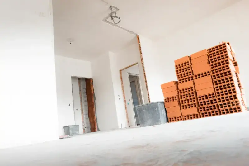 Materiały budowlane, w tym cegły, czekają na remont. Wnętrze domu w trakcie prac, przygotowanie do tego, jak wyrównać ściany w starym domu.