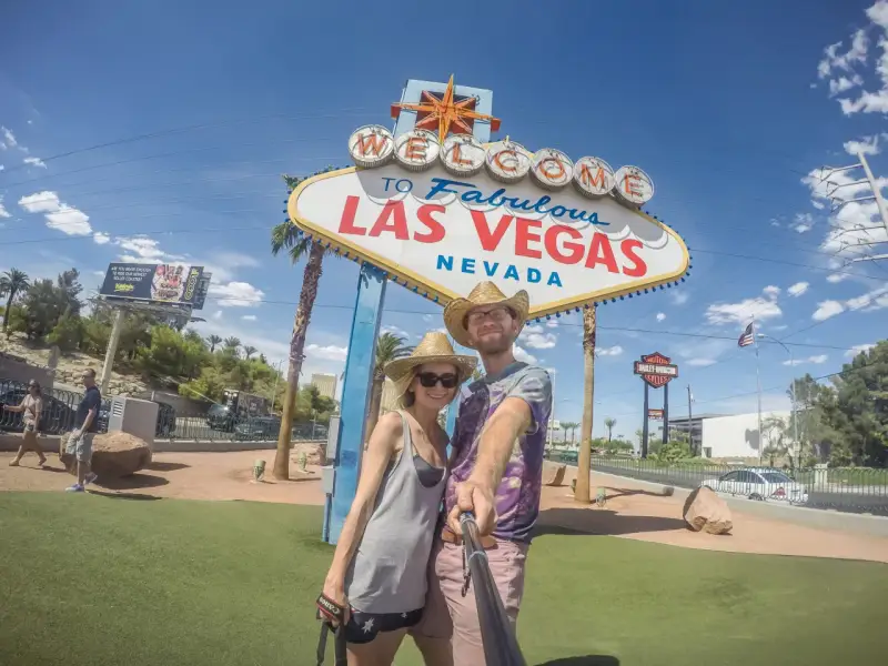 Para co przywieźć ze Stanów? Pamiątkę z Las Vegas! Uśmiechnięta para pozuje do selfie pod słynnym znakiem.