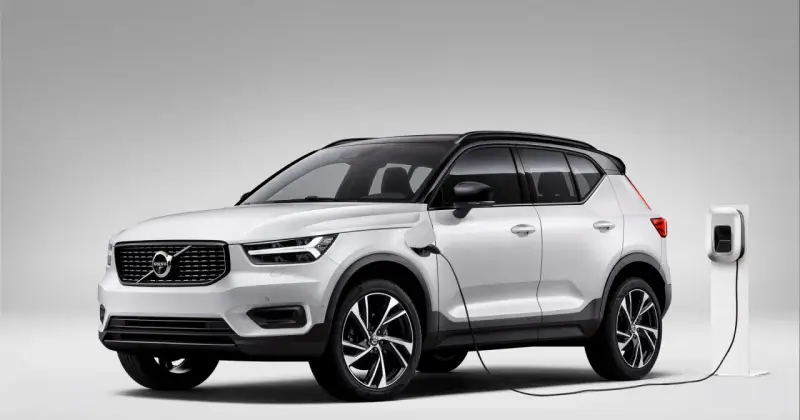 Biały Volvo XC40 Recharge plug-in hybrid podłączony do ładowarki.