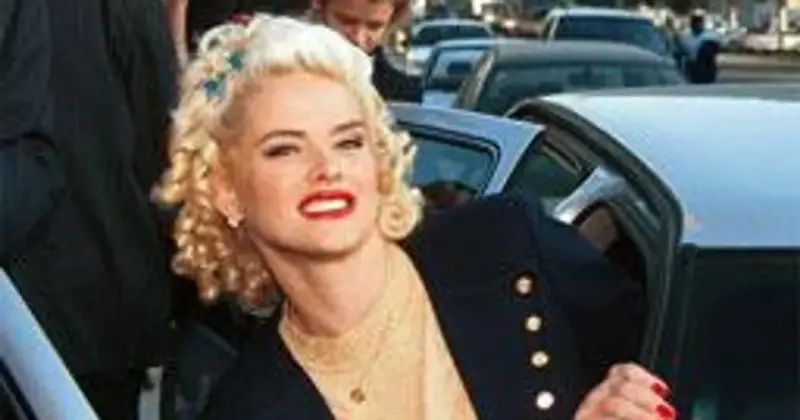 Anna Nicole Smith, z burzą blond loków i czerwoną szminką, wysiada z samochodu.