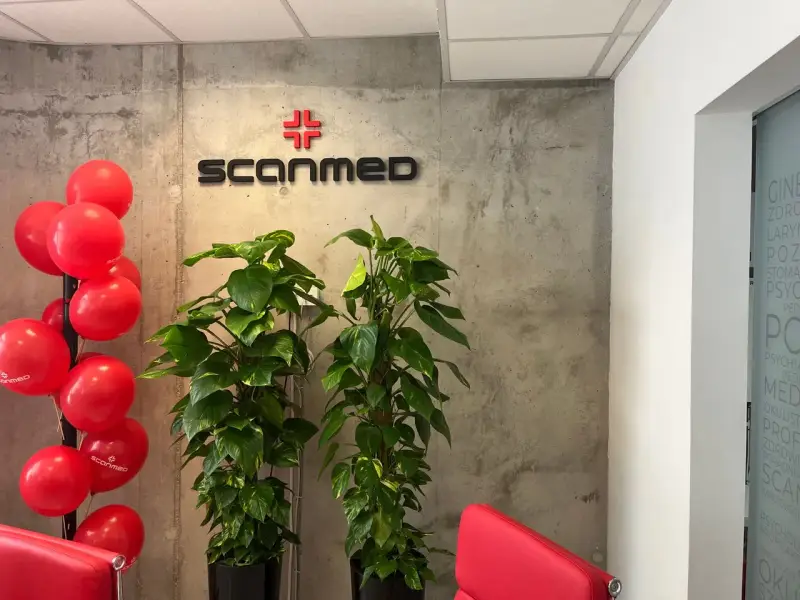 Czerwone balony, logo Scanmed i rośliny w nowoczesnym wnętrzu kliniki medycznej.