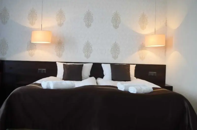 Przytulny pokój hotelowy z podwójnym łóżkiem, białymi ręcznikami i lampami. Czy można wynająć pokój w hotelu mając 17 lat?