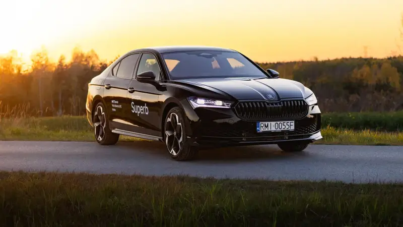 Czarny Skoda Superb 4 na tle zachodzącego słońca. Elegancki sedan z nowoczesnymi światłami i felgami.