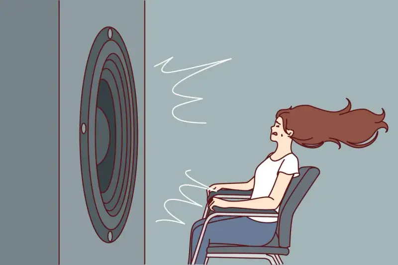 Une femme assise, les cheveux au vent, face à un haut-parleur. Le son est si fort qu'il en devient une force physique, illustrant la définition du décibel.