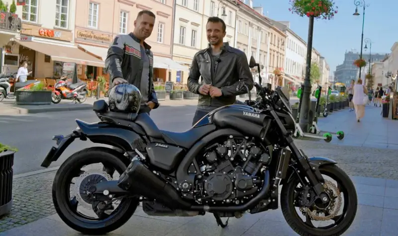 Dwóch mężczyzn pozuje obok czarnego motocykla Yamaha V-Max 1700 na ulicy.