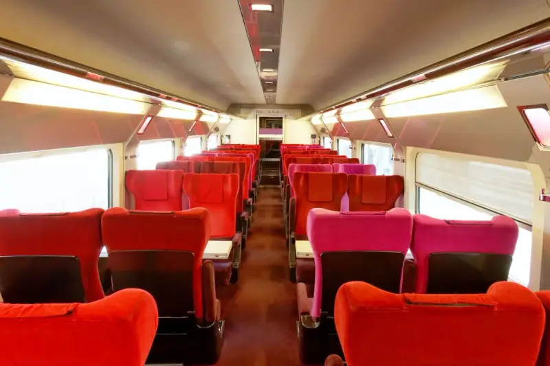 Rows of red and pink seats inside a train car, ready for passengers on the best train from Amsterdam to Paris.