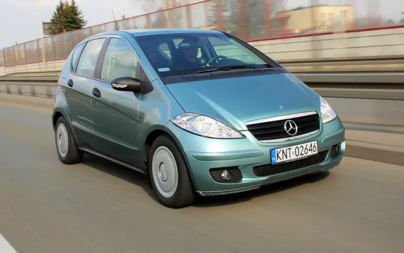 Turkusowy Mercedes A170 na drodze, z widocznym kierowcą.