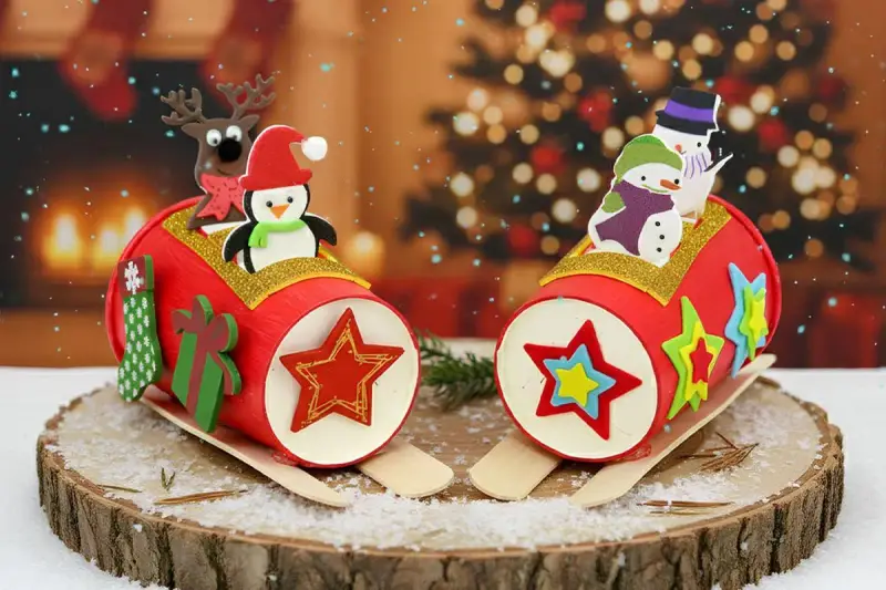 Deux traîneaux de Noël en carton décorés de pingouins, bonhommes de neige et rennes, sur un fond festif.