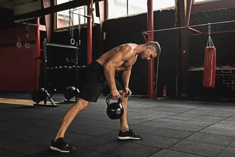 Mężczyzna wykonuje trening funkcjonalny ćwiczenia z kettlebell w siłowni.