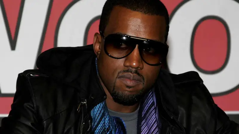 Kanye West w okularach przeciwsłonecznych i skórzanej kurtce, gotowy na koncert w Polsce.