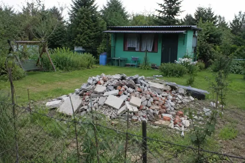 Kupa gruzu na działce ROD. Czy komornik może zająć działkę ROD? W tle zielona altanka, huśtawka i drzewa.