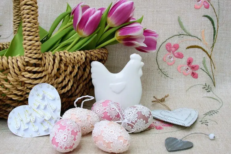 Wielkanocne dekoracje: koszyk z tulipanami, ceramiczna kurka, ozdobne jajka i serca.
