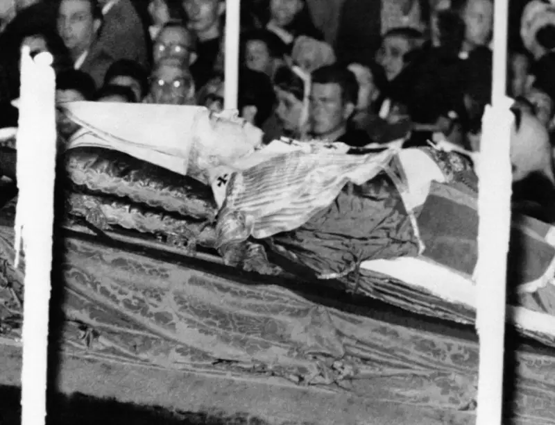 Pius XII w szatach, przygotowany do balsamowania. Tłum ludzi w tle.