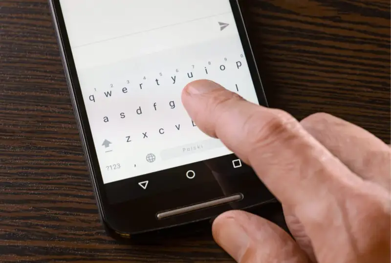 Palec naciska klawisz "Polski" na klawiaturze telefonu, aby ustawić polskie znaki w SMS.
