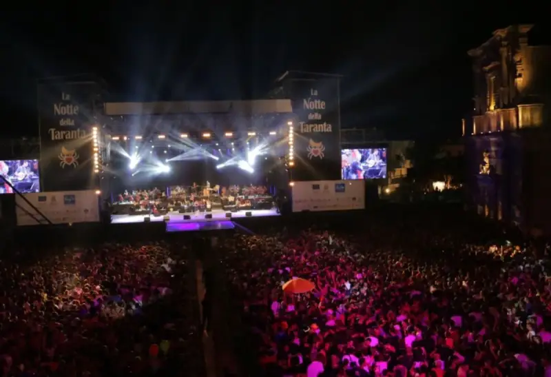 La Notte della Taranta, un'enorme folla festeggia sotto un palco illuminato. Le feste di settembre in Puglia sono magiche!