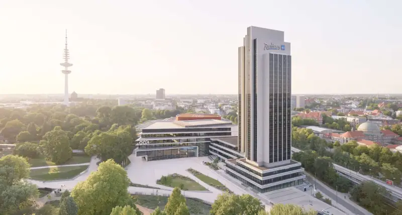 Radisson Blu Hotel w Hamburgu, z wieżą telewizyjną w tle, otoczony zielenią.
