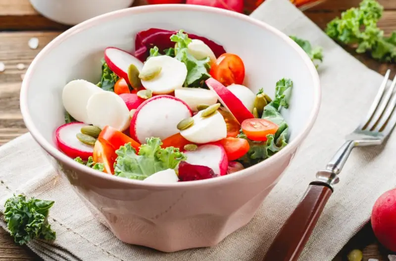 Świeża sałatka do grilla w 3 minuty: rzodkiewka, pomidorki, ser mozzarella i pestki dyni w misce.