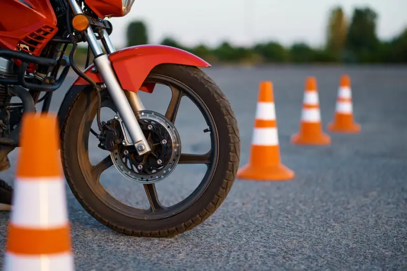 Czerwony motocykl i pomarańczowe pachołki na placu manewrowym. Przygotowanie do egzaminu na kategorie prawa jazdy na motor.