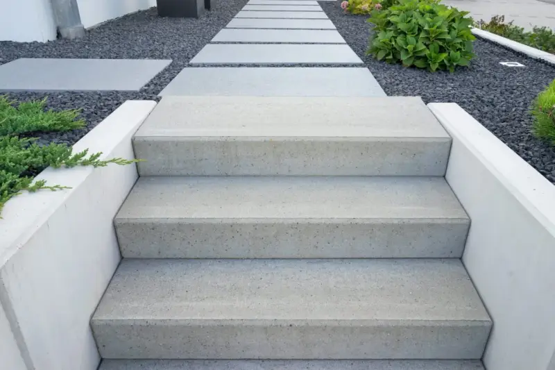Nowe schody do ogrodu zrób sam. Nowoczesne, betonowe stopnie prowadzą przez kamienny żwirek do zieleni.