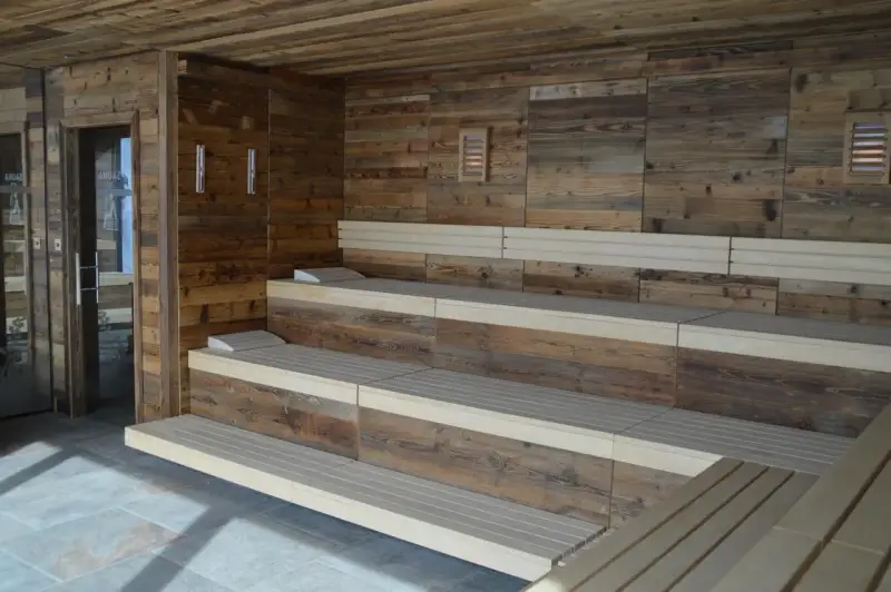 Drewniana sauna w domu z wielopoziomowymi ławami i kamienną podłogą. Idealne miejsce na relaks.