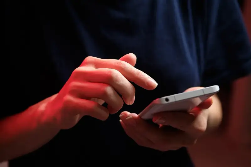 Dłonie z czerwonym podświetleniem obsługują smartfon, być może ustawiając **direct debit** na rachunki.
